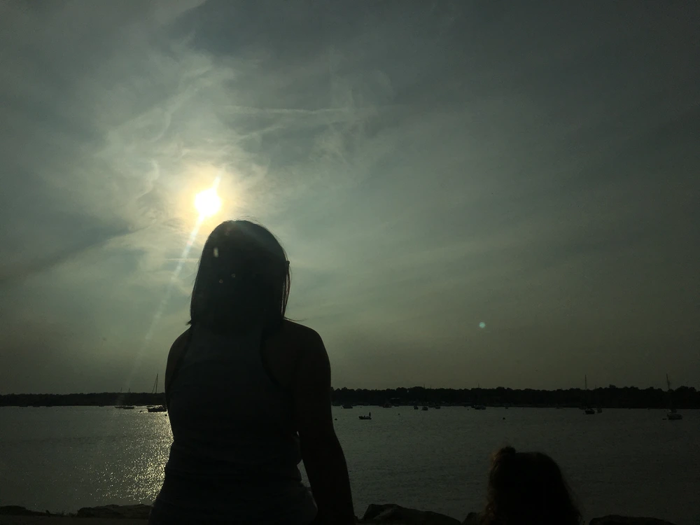photo silhouette of woman looking out over a sunset reflecting on living loss